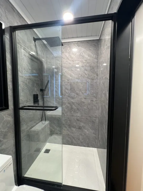Glass shower with grey stone-look tile and black fixtures