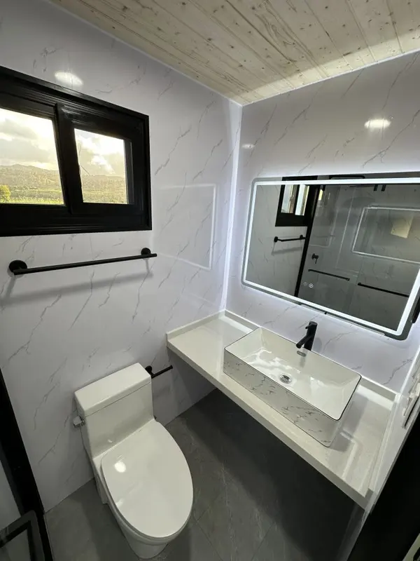Bathroom with a marble-look vanity, a backlit mirror and a window onto green hills