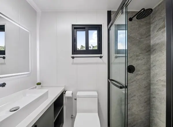 Bathroom with a wide mirror, a white vanity and a grey-tiled walk-in shower