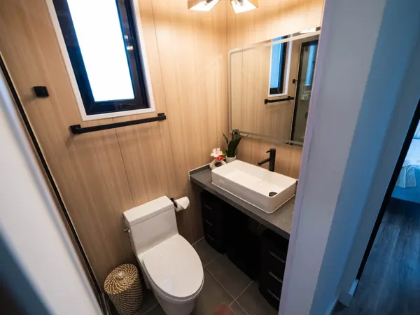Warm wood-look bathroom with a white vessel sink and black fixtures