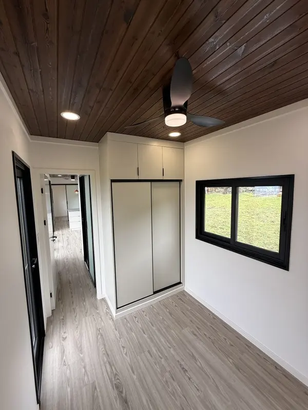 Bedroom with a built-in closet under a dark wood ceiling and a window onto the yard