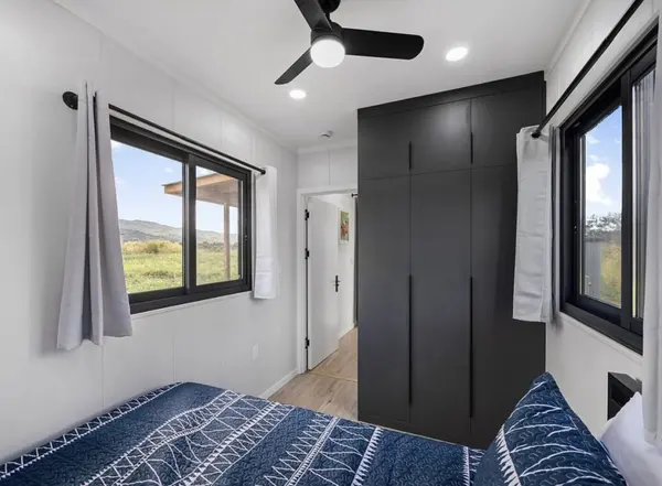 Bedroom with navy bedding, a black wardrobe and windows on two walls