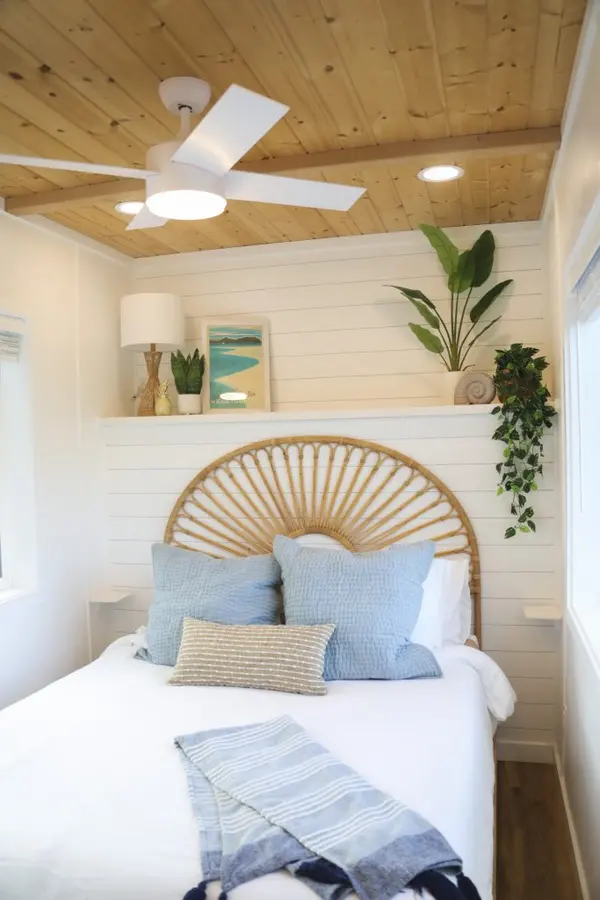 Bedroom with a rattan sunburst headboard, white shiplap walls and a pine ceiling