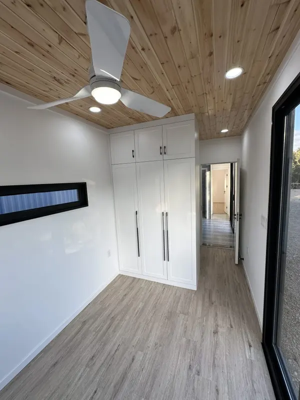 Bedroom with a tall white wardrobe, a pine ceiling and a sliding glass door
