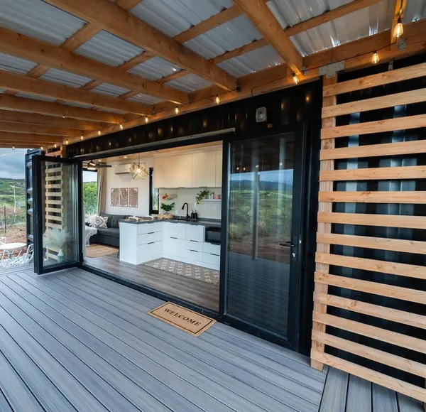 Covered deck with glass folding doors open to a white kitchen and living area