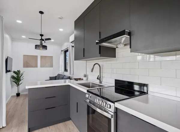 Charcoal kitchen with a stainless range and white subway tile, with the living area beyond