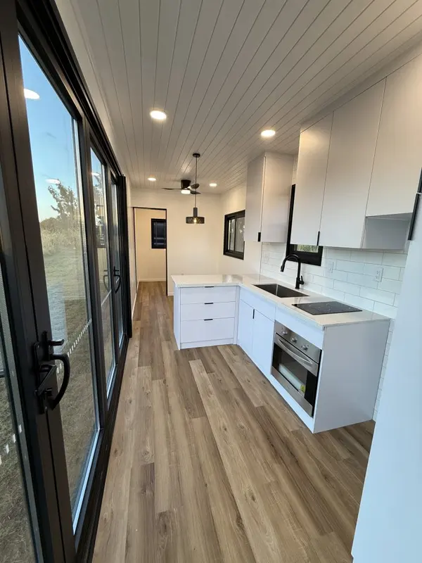 White kitchen at the end of a room lined with glass doors