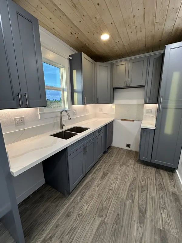 Grey shaker kitchen with a double sink and under-cabinet lights beneath a pine ceiling