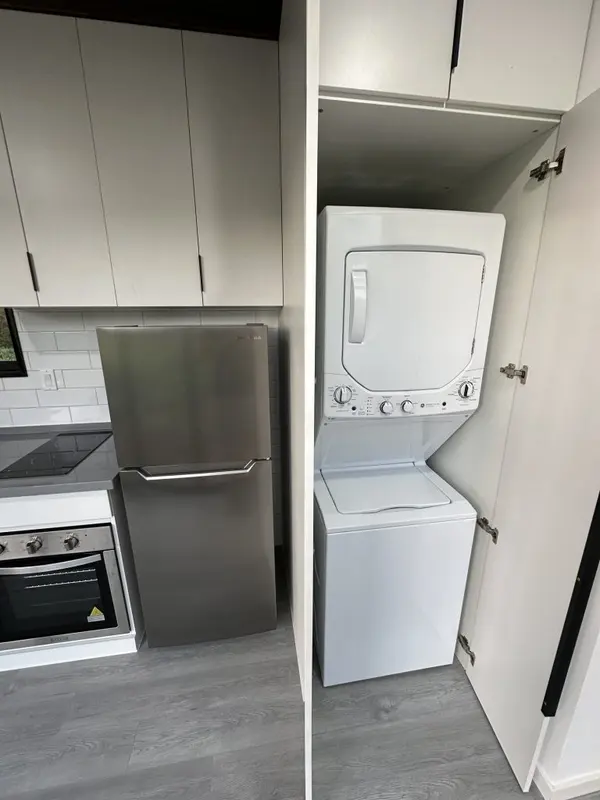 Stacked washer and dryer tucked into a cabinet beside the fridge