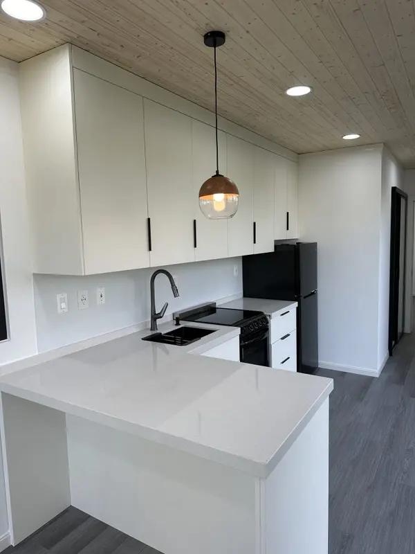 White kitchen with a quartz peninsula, black range and a copper pendant light