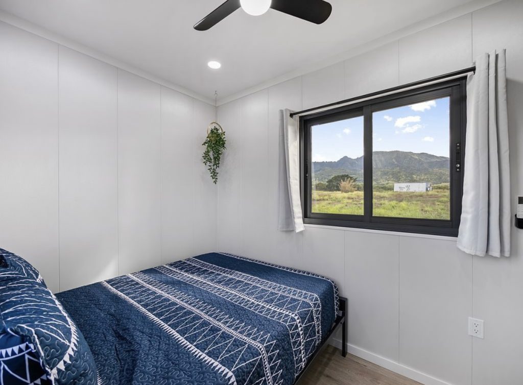 Bedroom with navy patterned bedding and a window framing mountain views