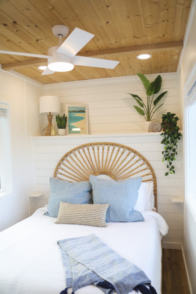 Bedroom with a rattan sunburst headboard, white shiplap walls and a wood ceiling