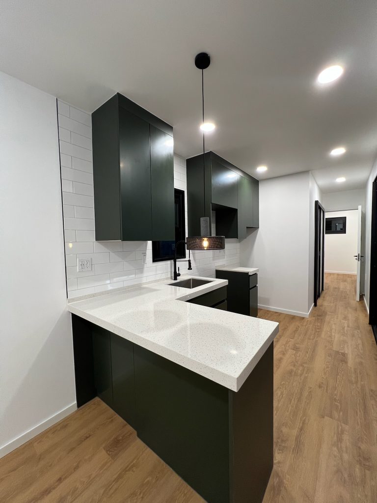 Dark green kitchen with white subway tile and a wood-look floor
