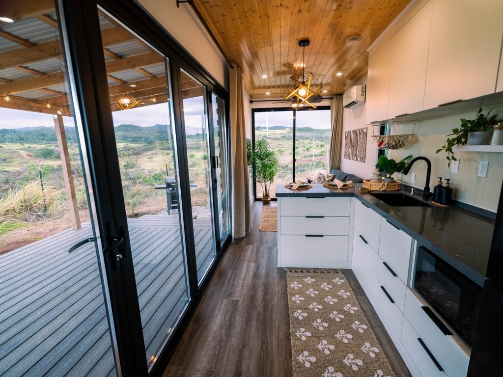 Kitchen and living area opening onto a wooden deck with views of green hills
