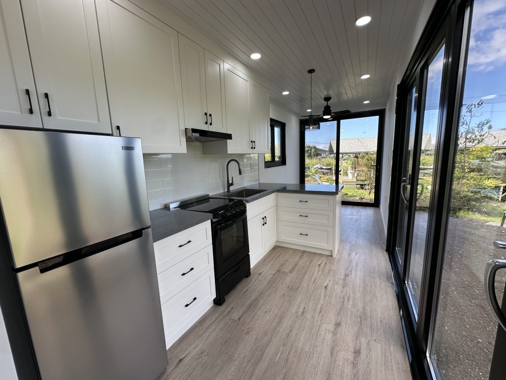 White kitchen with a stainless fridge and a wall of glass doors onto a green yard