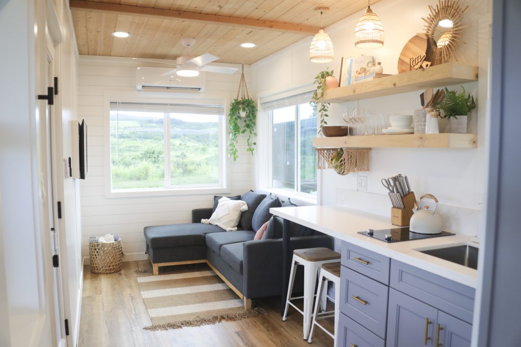Bright living area with a blue-grey sofa, floating shelves and a window onto green hills